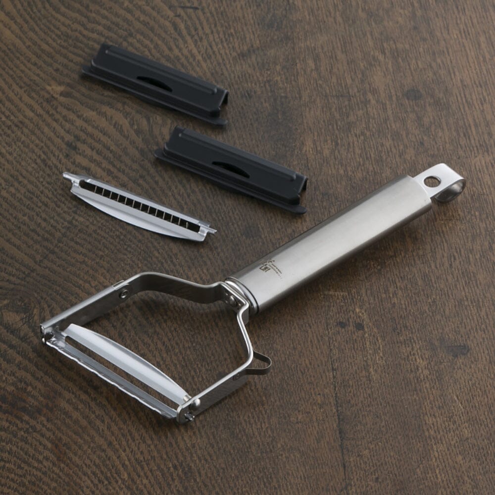Metal peeler with attachments on a wooden surface
