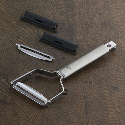 Metal peeler with attachments on a wooden surface
