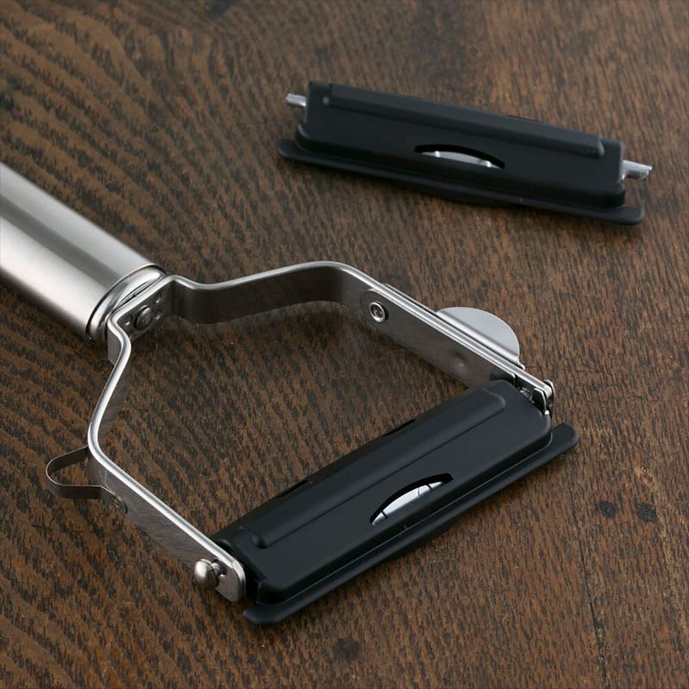 Metallic kitchen tool with black components on a wooden surface