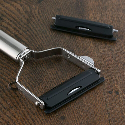 Metallic kitchen tool with black components on a wooden surface