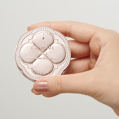 Hand holding a Canmake makeup product against a light background